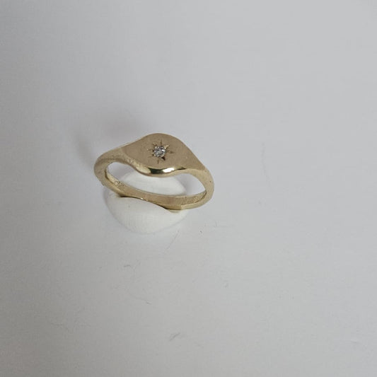 Gold ring with a small diamond on a white background