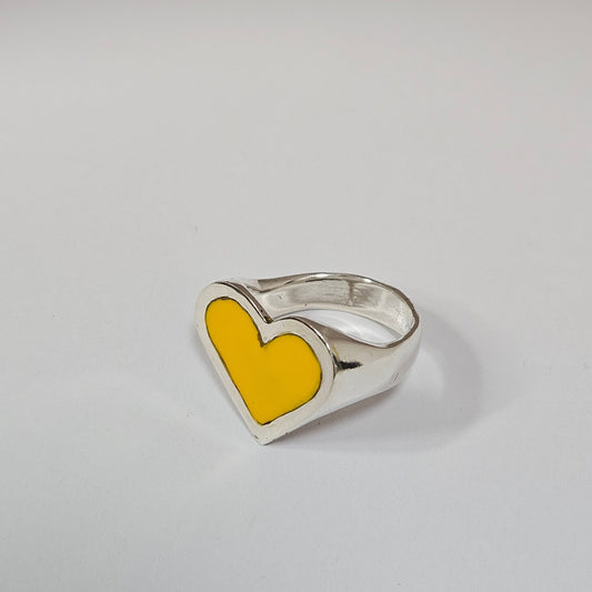 Silver ring with a yellow heart-shaped inset on a light gray background