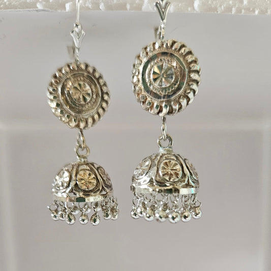 Pair of silver earrings with intricate designs on a light gray background